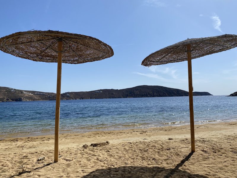 Twee rieten parasols aan een blauwe baai