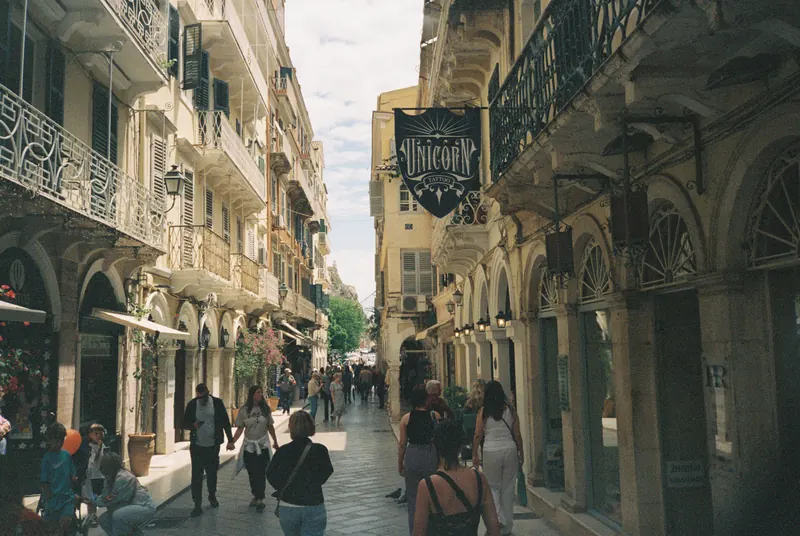 A sunlit street with arcades and iron balconies